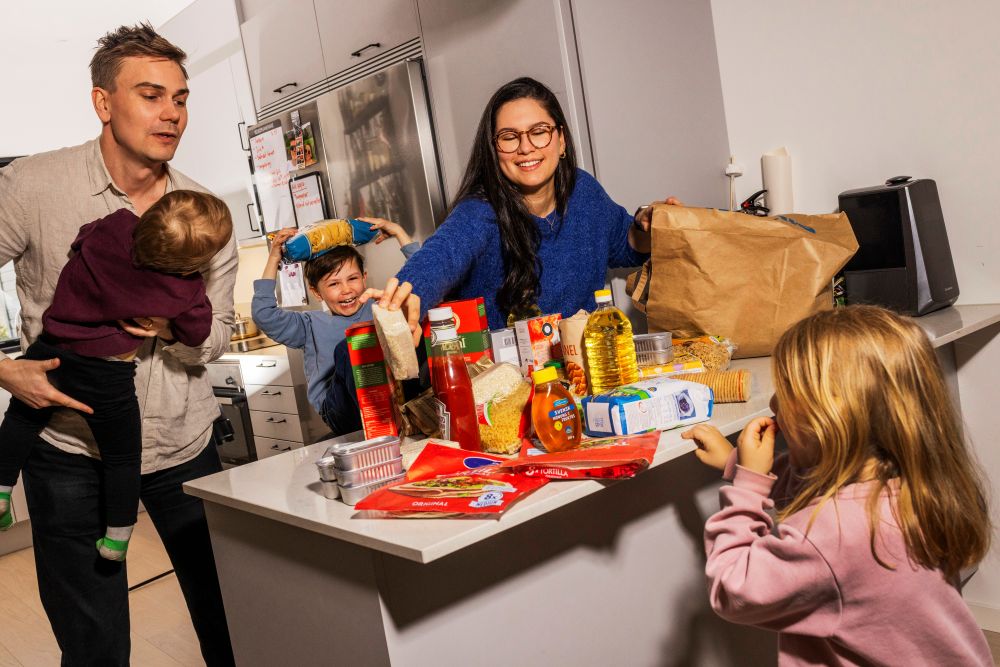 En bild på en mamma och en pappa samt tre barn som har handlat matvaror som står på ett bord.