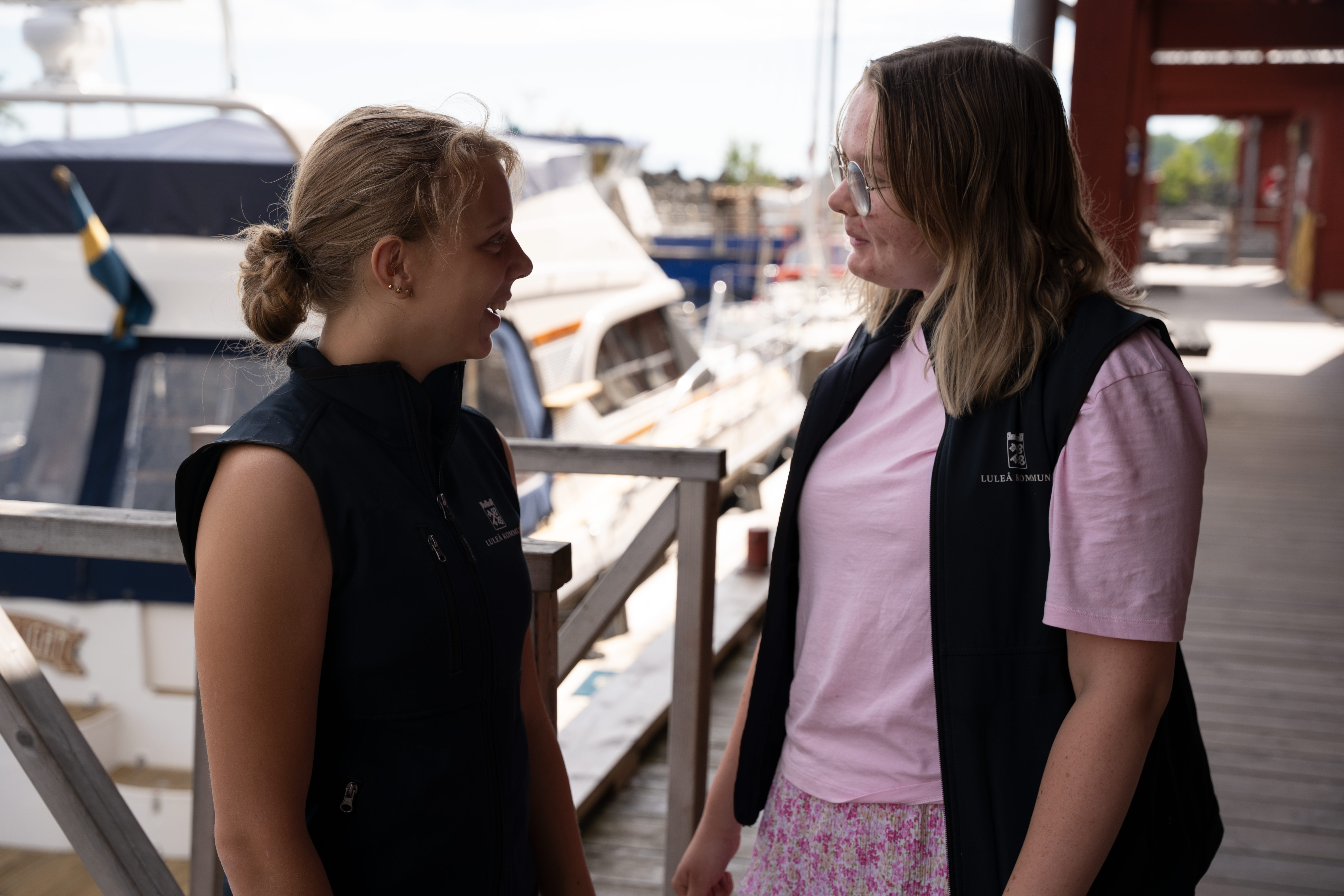 tvu ungdommar framför båtar i en hamn.