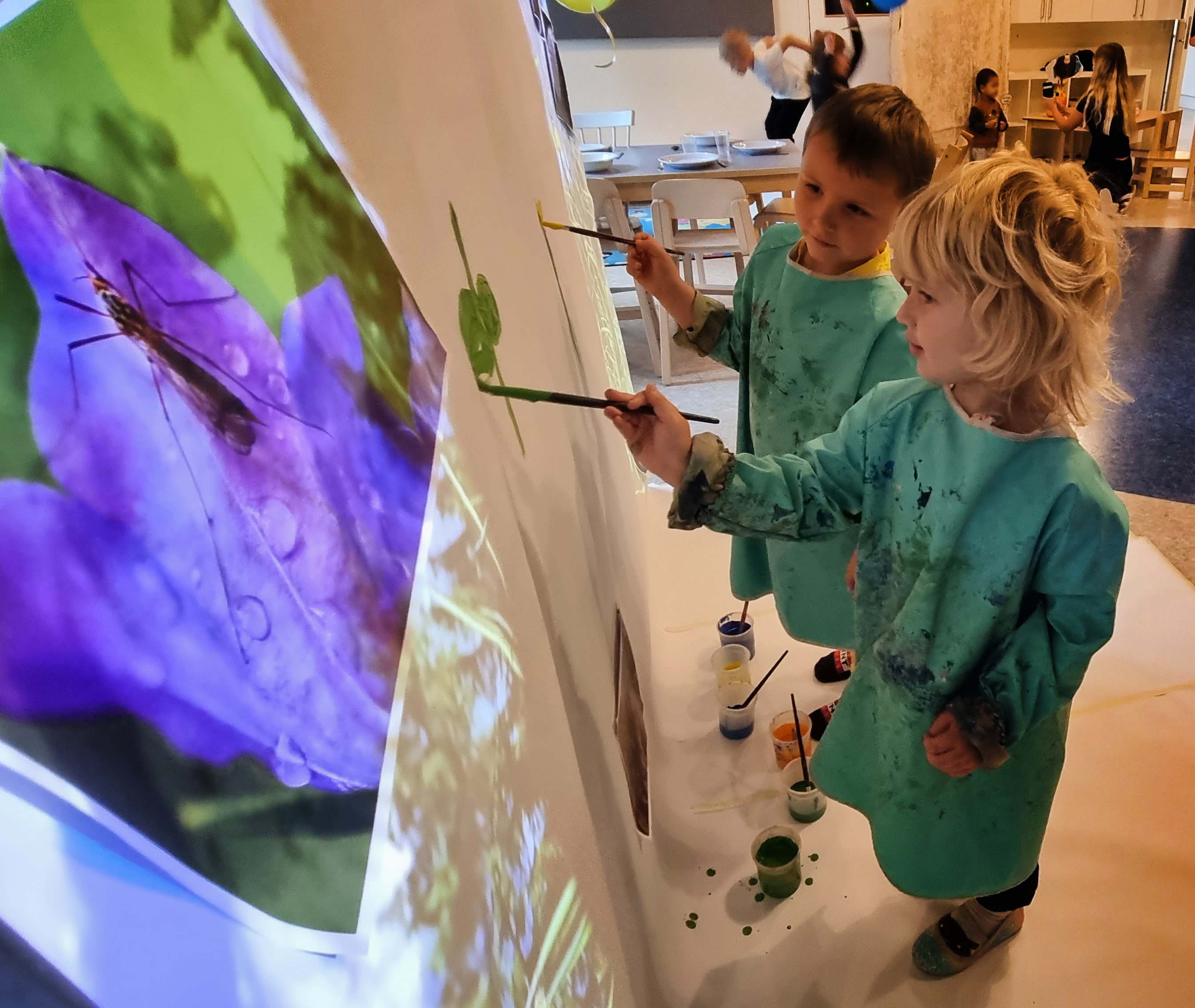 Barn målar växter på en äng som projicerats på en duk