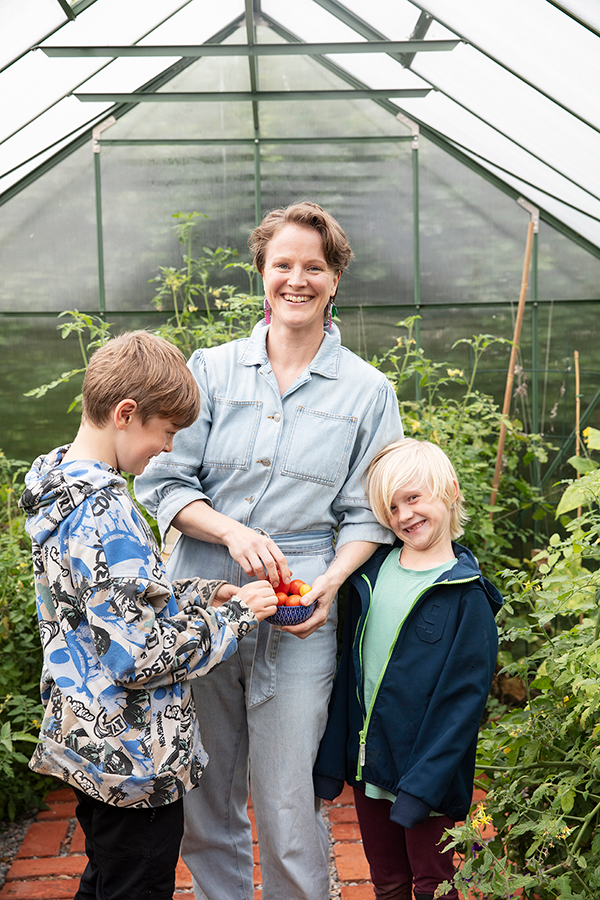 Mamma och två barn i ett växthus