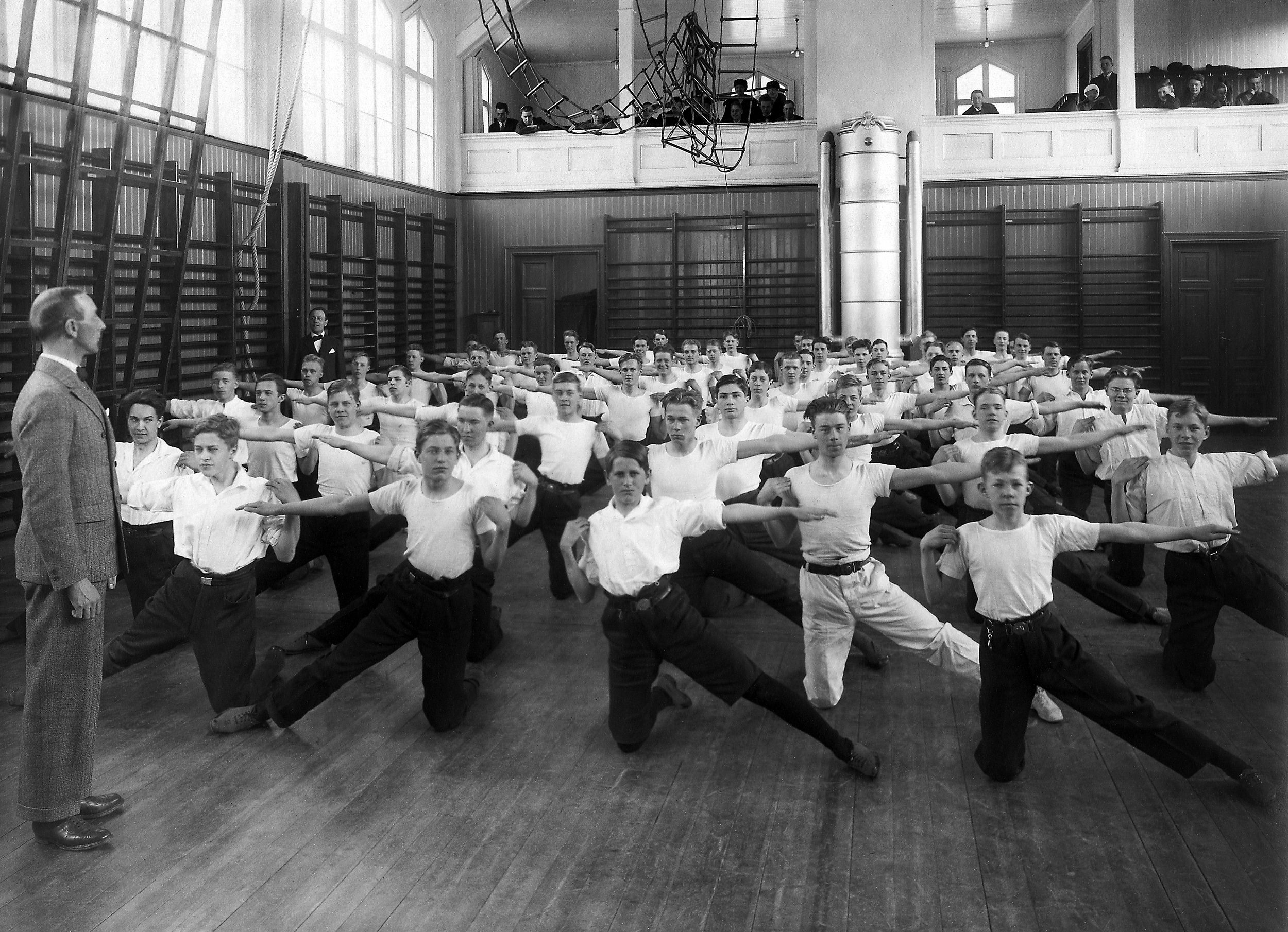 Pojkar i gymnastiksal står på knä och sträcker armarna utåt.