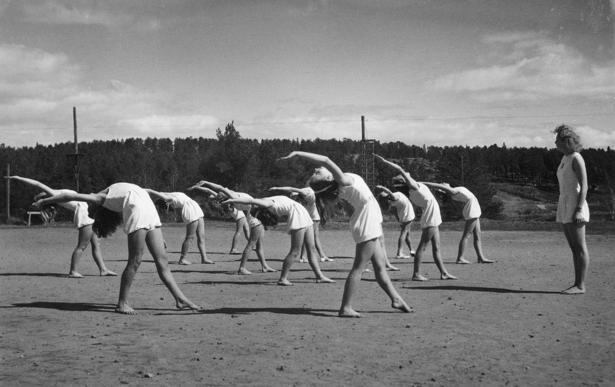 Gymnastikgrupp med flickor som böjer ryggarna bakåt i en båge.