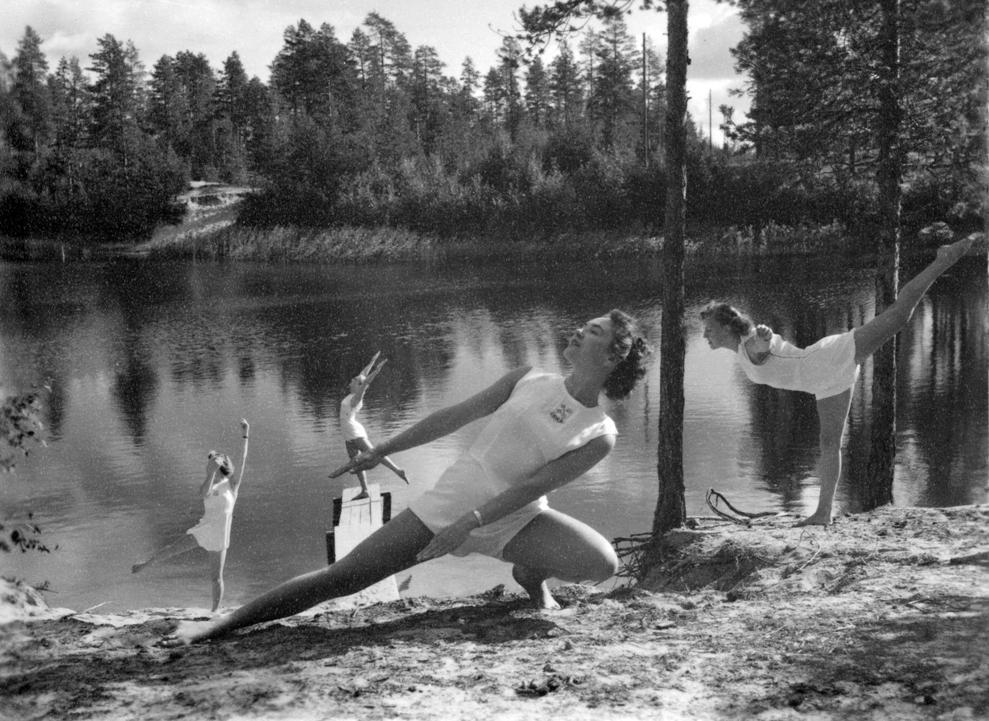 Kvinnliga gymnaster i vackra poser vid en skogstjärn.