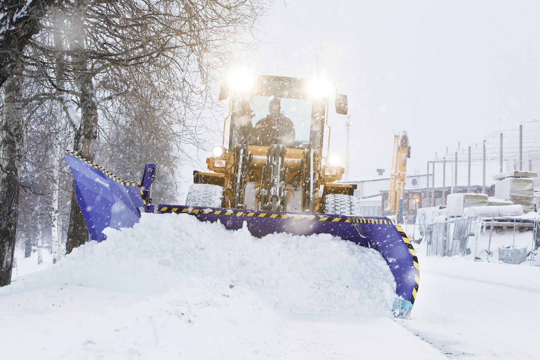 Bild på en traktor som tar bort snö från en väg. 