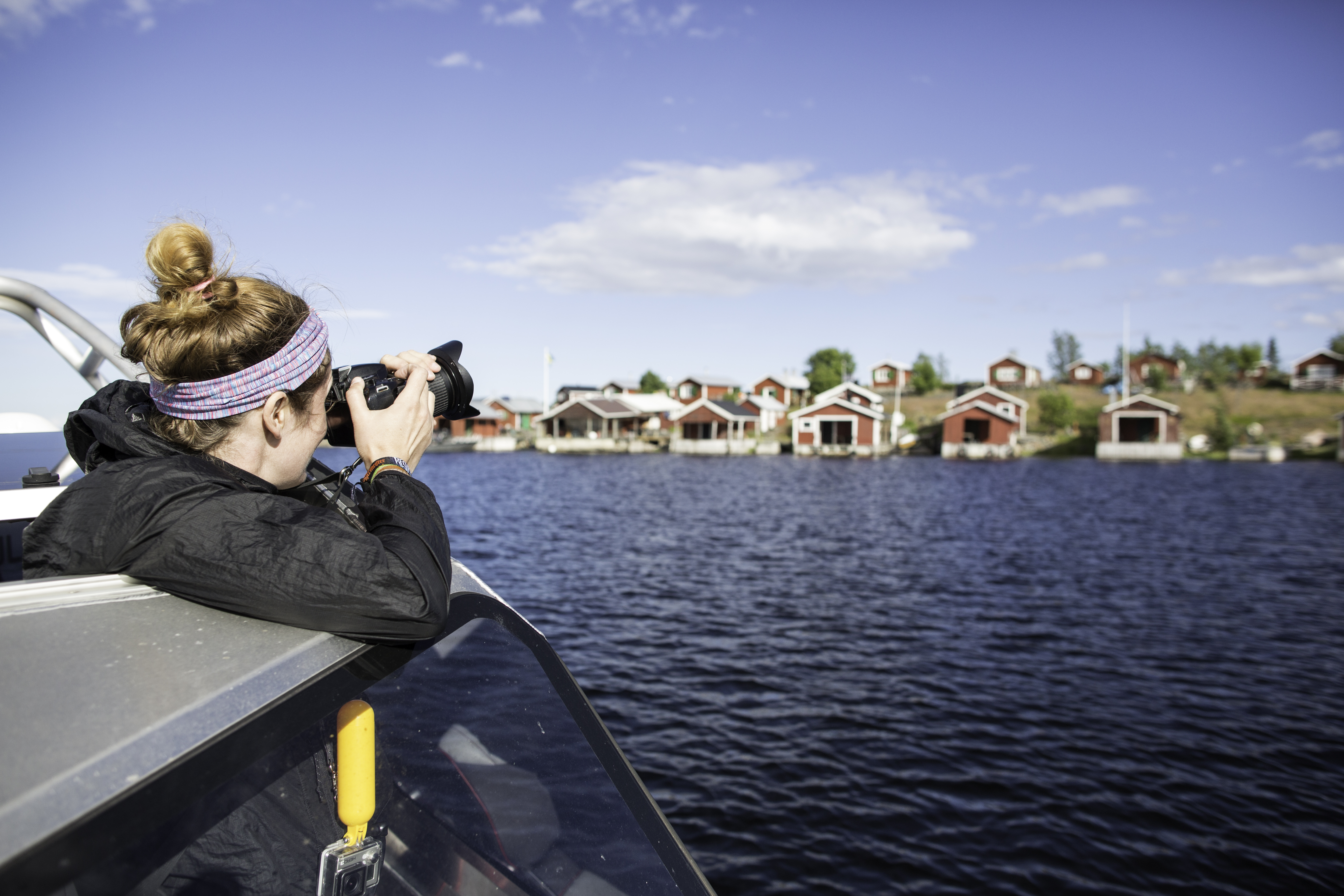 Någon åker båt och tar ett foto från båten, mot någon skärgårdsö i Luleå med små röda stugor.