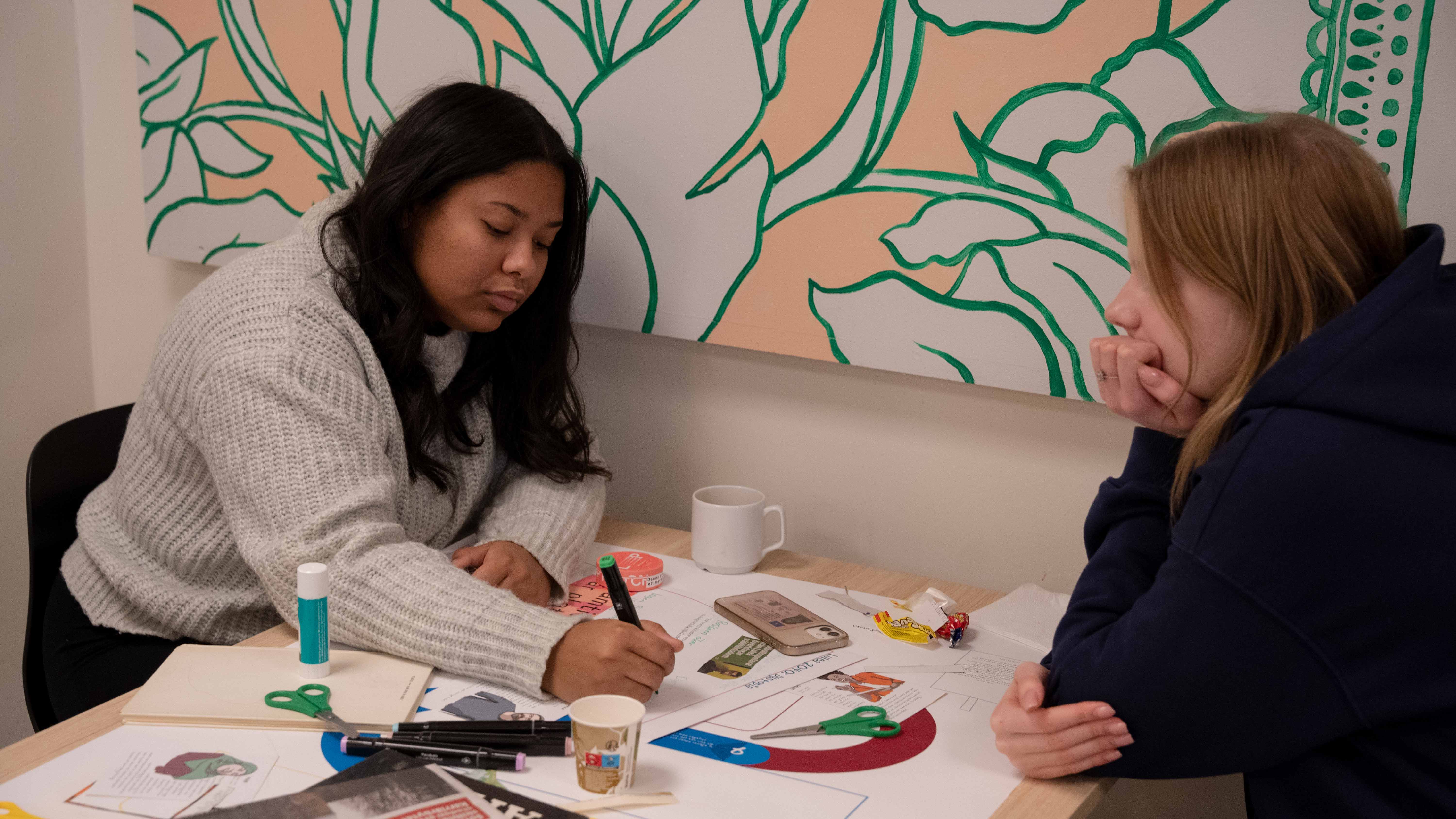 två unga kvinnor som sitter vid ett bord.