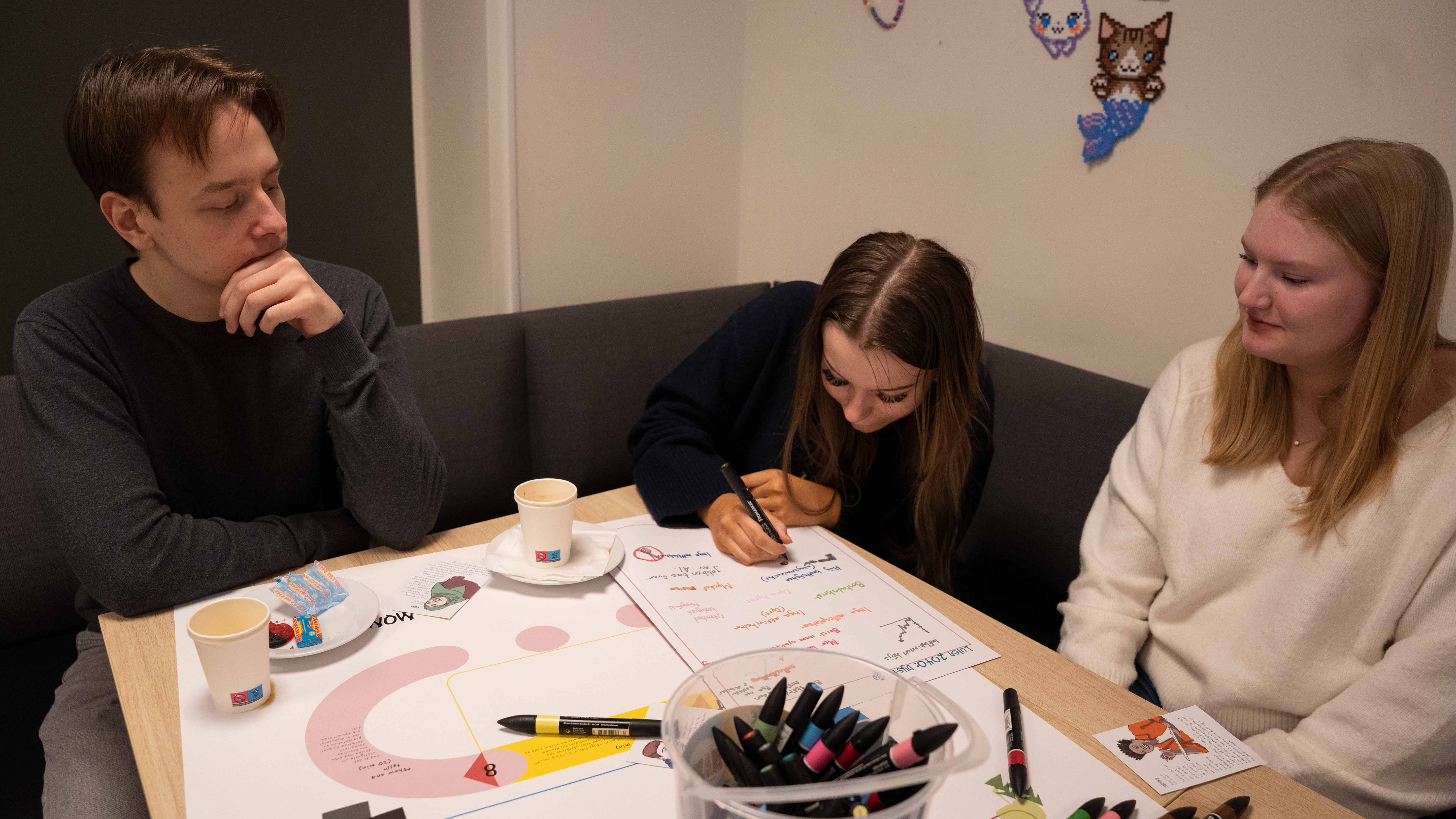 tre unga personer som sitter vid ett bord.