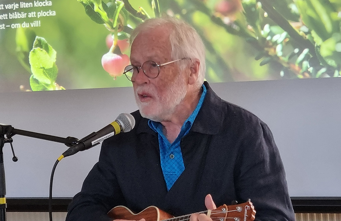 Föreläsaren Thomas Öberg sitter och spelar ukulele och sjunger en visa om skogen.