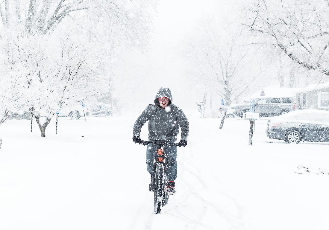 cyklist på en igensnöad väg i kraftigt snöfall