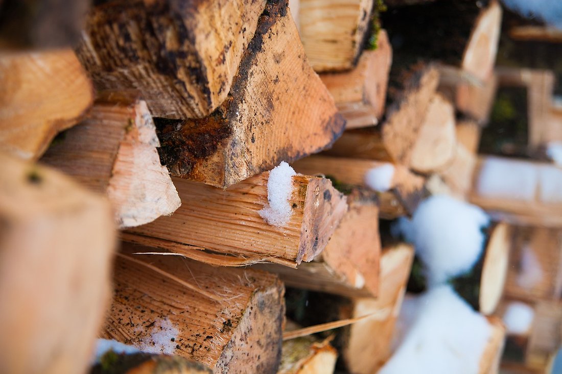 Bild på staplad ved med lite snö på