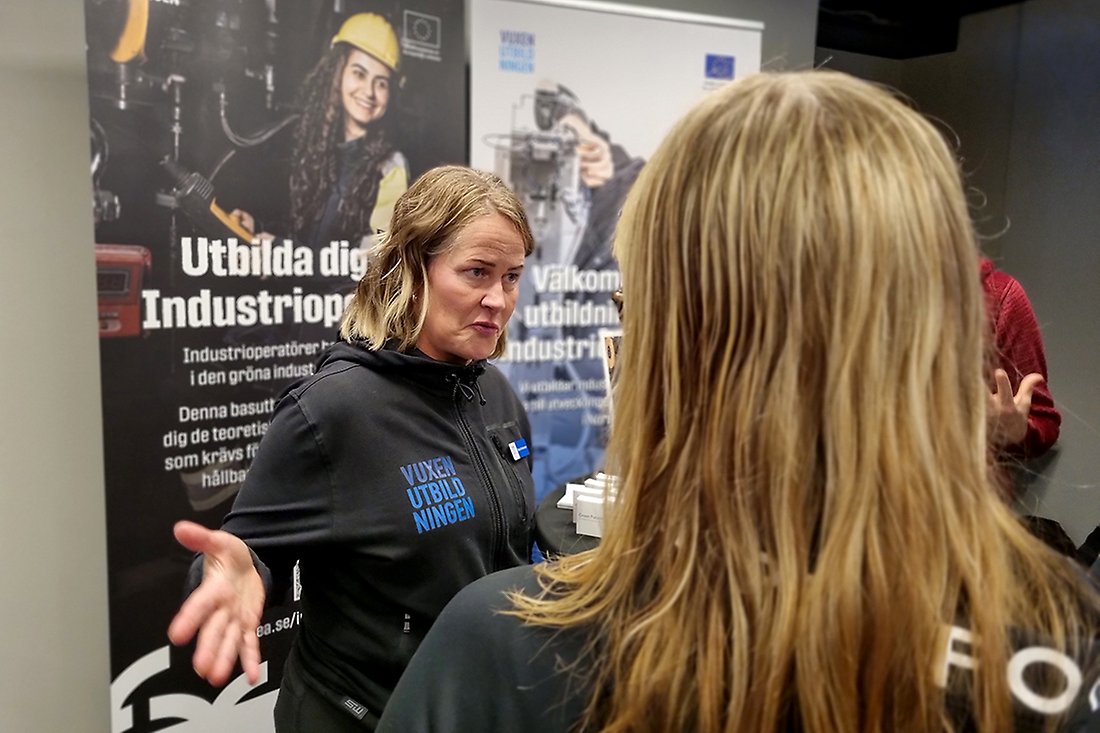 Kvinna medVuxenutbildningens emblem på tröjan står och pratar
