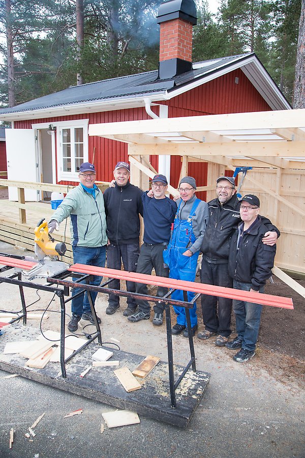 ett gäng gubbar framför en stuga