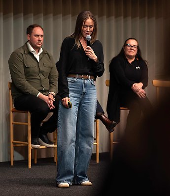 en kvinna på en scen, flera personer i bakgrunden