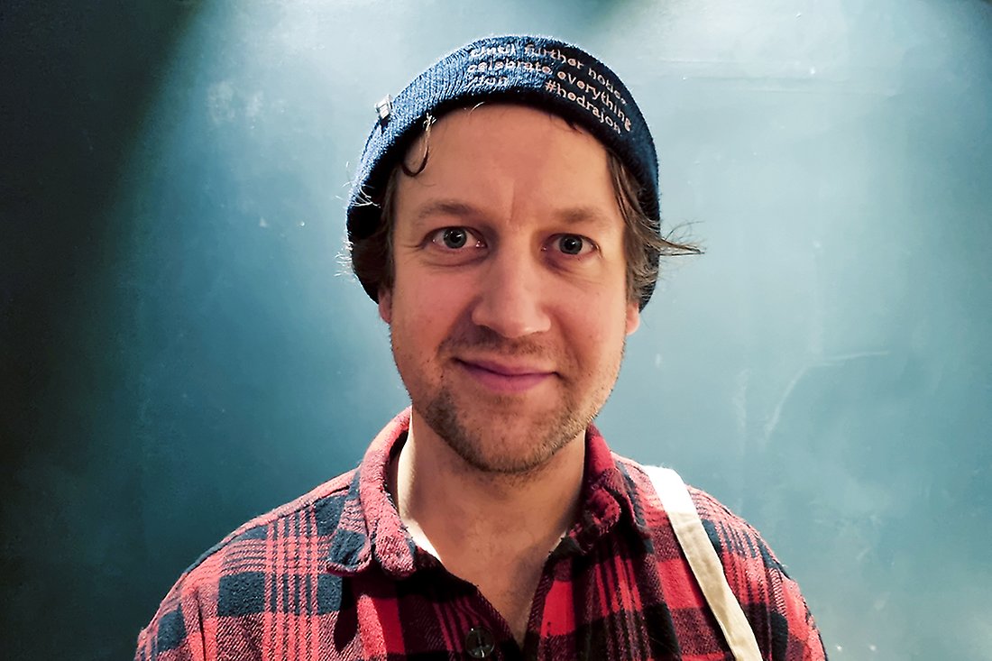 Ung man med rutig skjorta och mössa