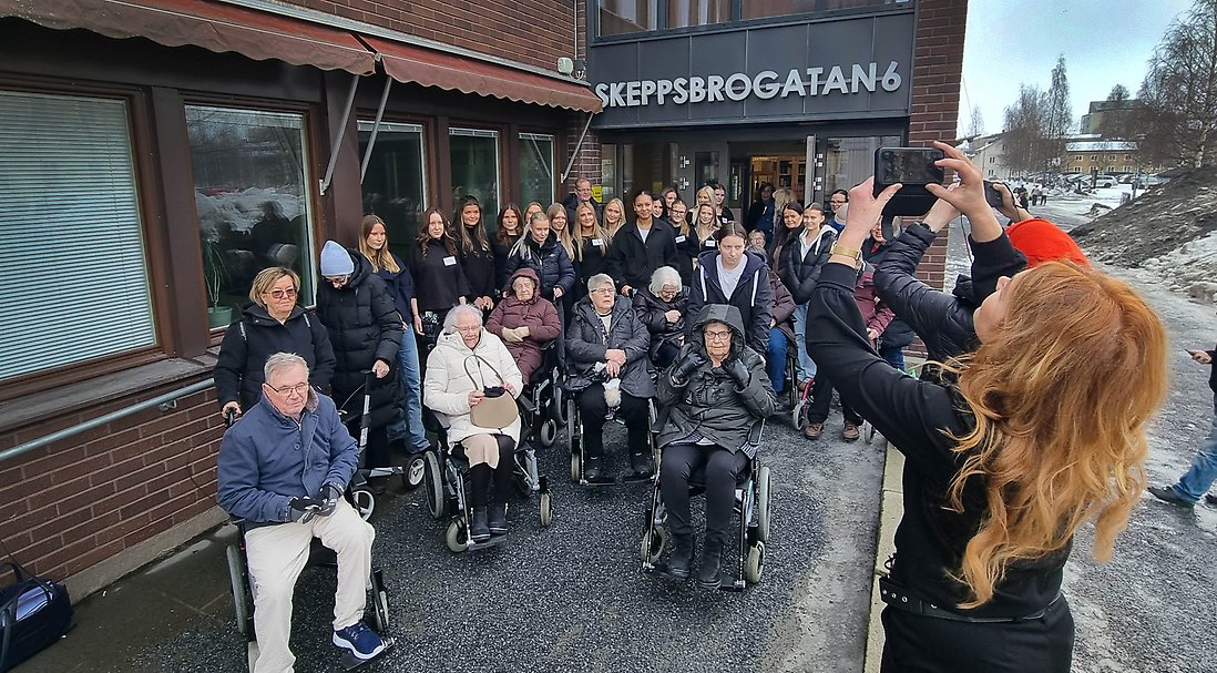 Elever och boende samlas för gruppfotografering av personalen och lokala medier.