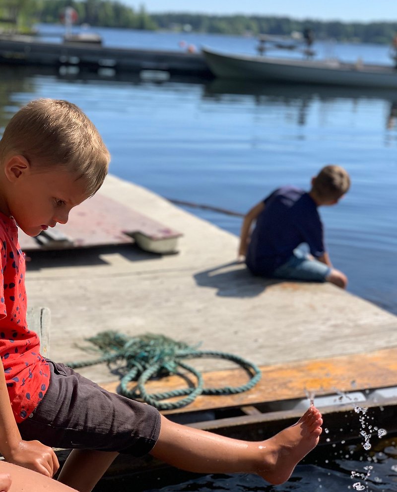 två pojkar doppar tårna i vatten